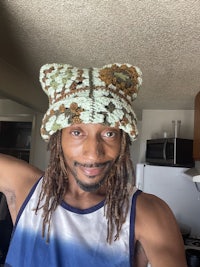 a man with dreadlocks wearing a crocheted hat